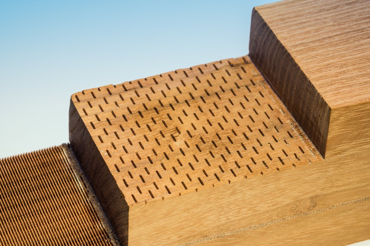 Stufig geschnittener Holzblock, an dessen Schnittkanten verschiedene Perforierungen zu erkennen sind.